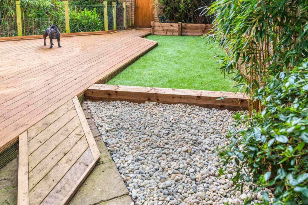 Artificial turf backyard with deck, stones and a dog