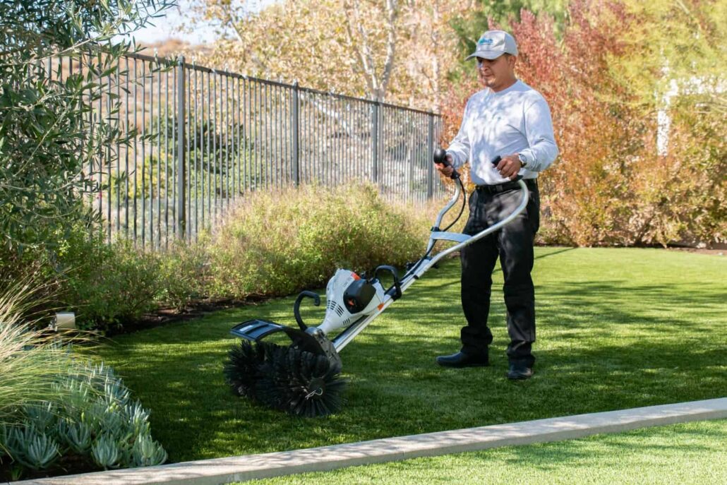 "A technician using professional equipment to deep-clean artificial turf, representing TurFresh’s eco-friendly, pet-safe service that eliminates odors and revitalizes outdoor surfaces."