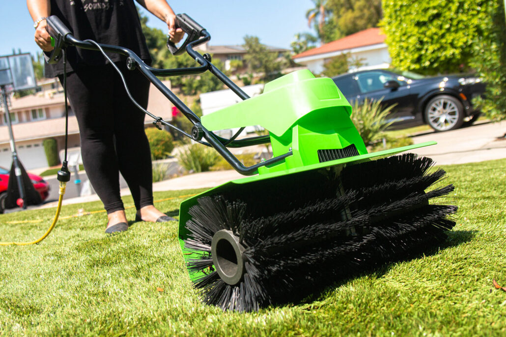 "A person using a professional-grade turf grooming machine on artificial grass, demonstrating TurFresh’s effective, pet-safe, and eco-friendly solution for eliminating odors and revitalizing outdoor spaces."