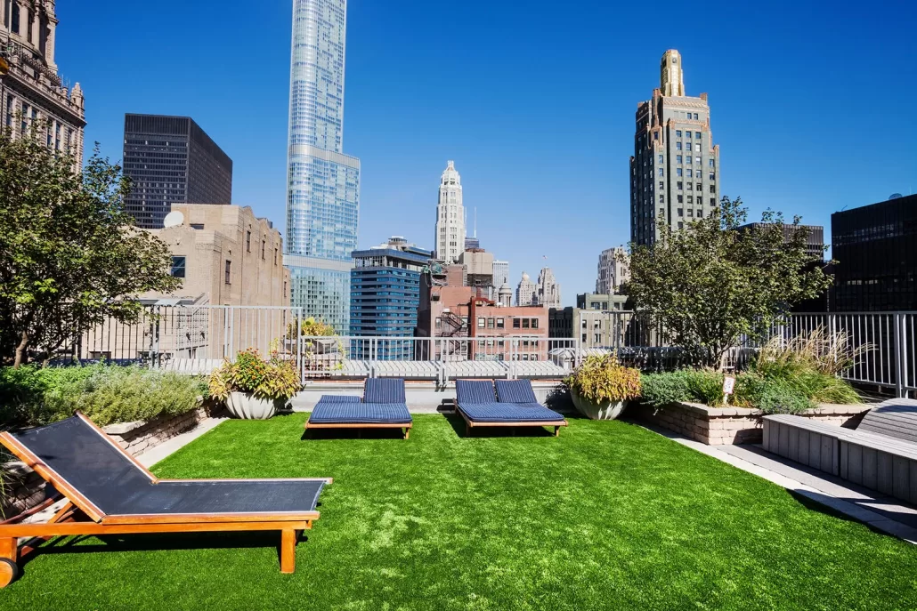 "Modern rooftop lounge with artificial turf and city skyline views, maintained with TurFresh’s professional-grade turf cleaner that eliminates odors, is eco-friendly, and safe for pets and people."