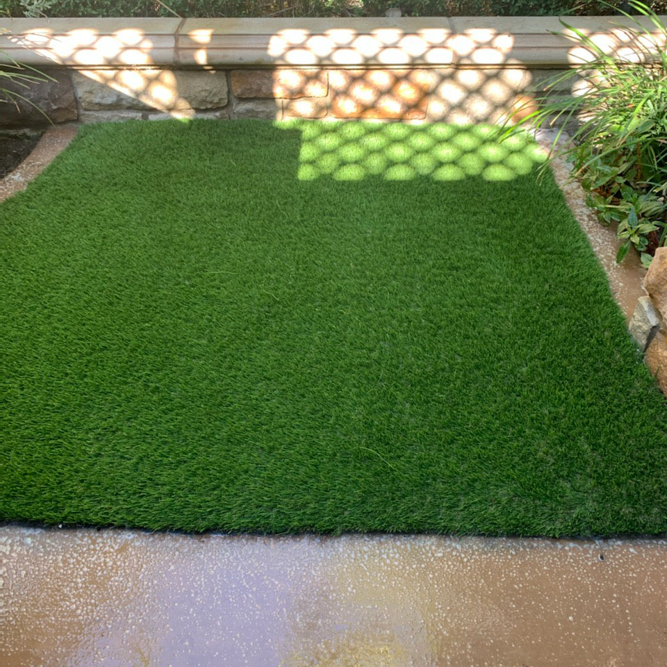 After-Side-Courtyard Image Alt Tag Generator said: Freshly cleaned artificial turf in a shaded patio area, ideal for low-maintenance outdoor living.