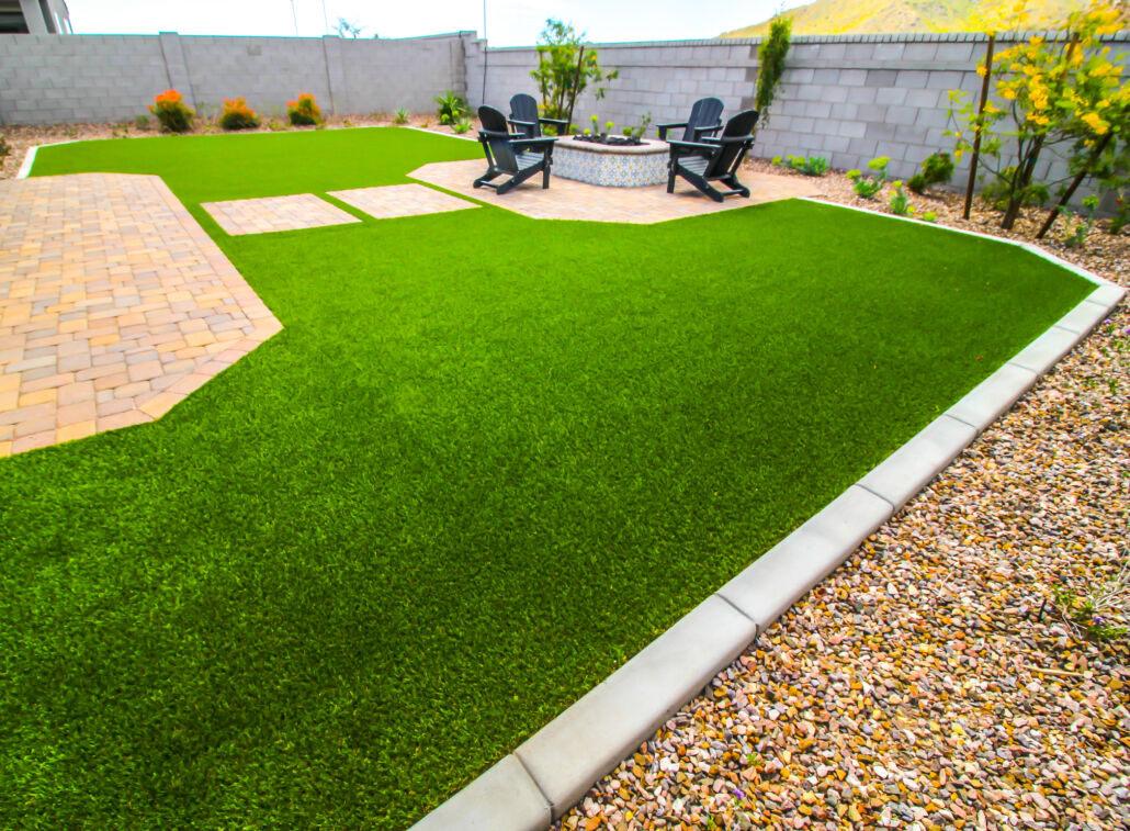 Clean and vibrant backyard with artificial grass and a patio fire pit area.