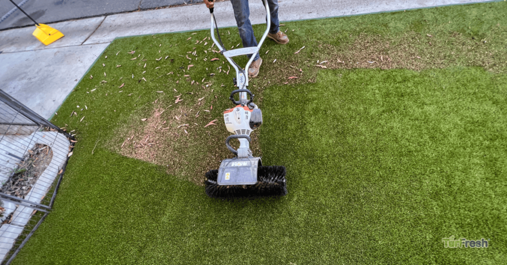 Overhead view of TurFresh technician power brooming dirty artificial turf to lift debris and rebloom fibers for a fresh green lawn