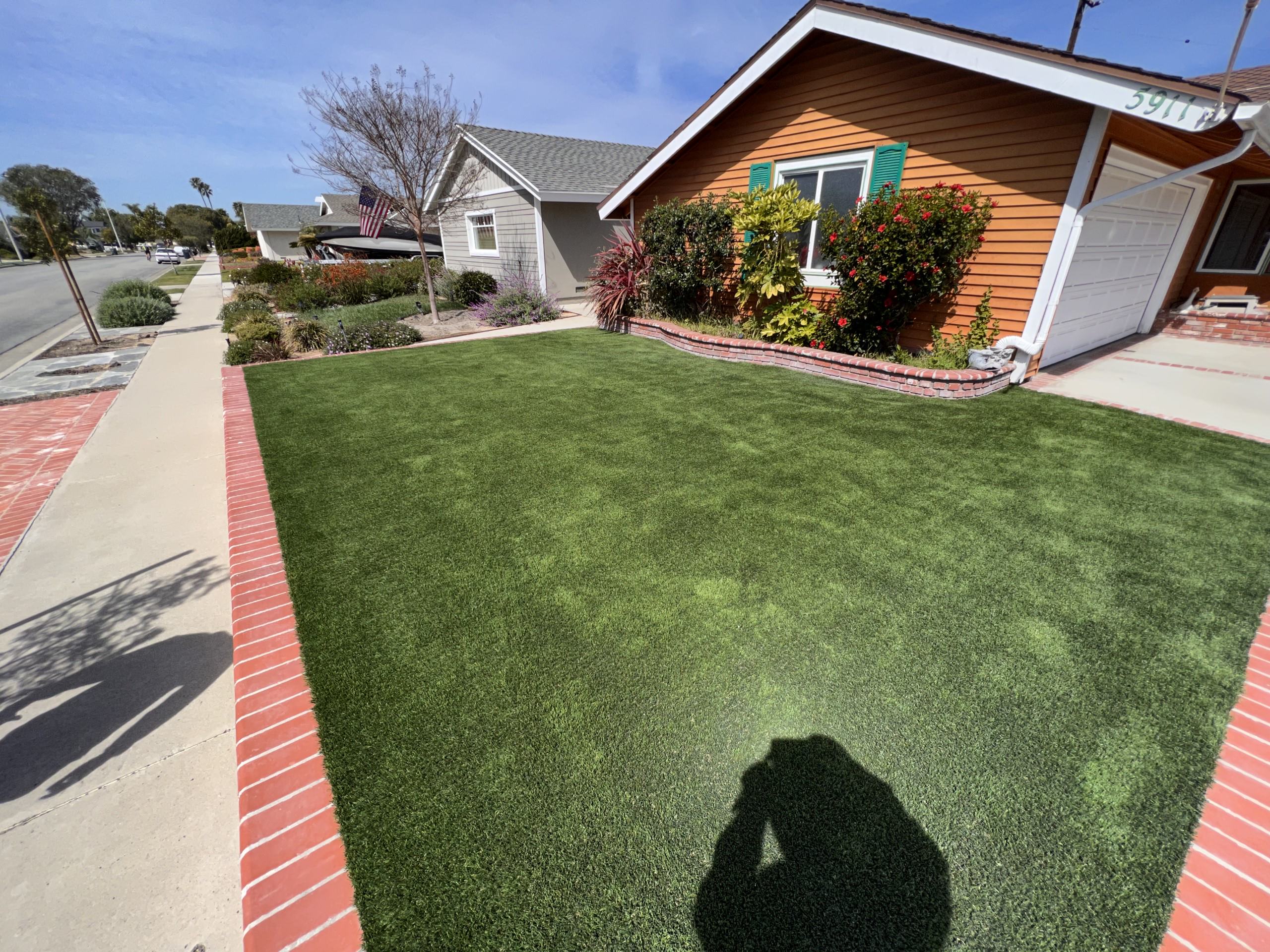 TurFresh artificial turf front yard lawn with brick border Front yard featuring clean, vibrant artificial turf maintained with TurFresh, highlighting a fresh, odor-free appearance achieved through eco-friendly, pet-safe turf cleaning and deodorizing.