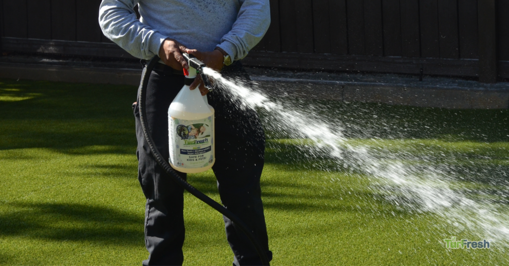 "Close-up of a professional applying TurFresh turf deodorizer, a non-toxic, biodegradable formula that safely eliminates odors and refreshes artificial grass for kids and pets."