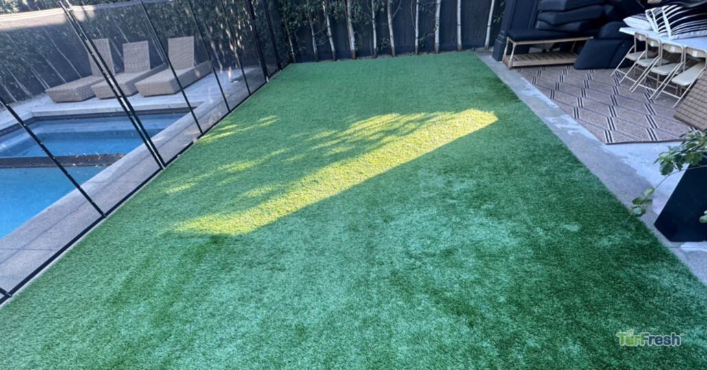 Artificial turf backyard near pool area after TurFresh cleaning showing bright, refreshed grass