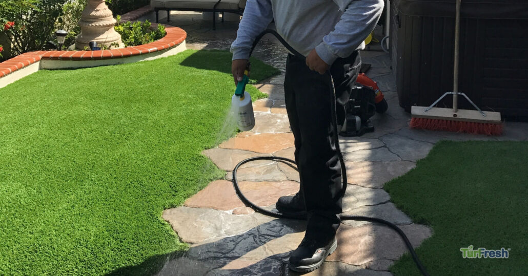 TurFresh professional applying turf cleaning solution on artificial grass to maintain odor control and freshness