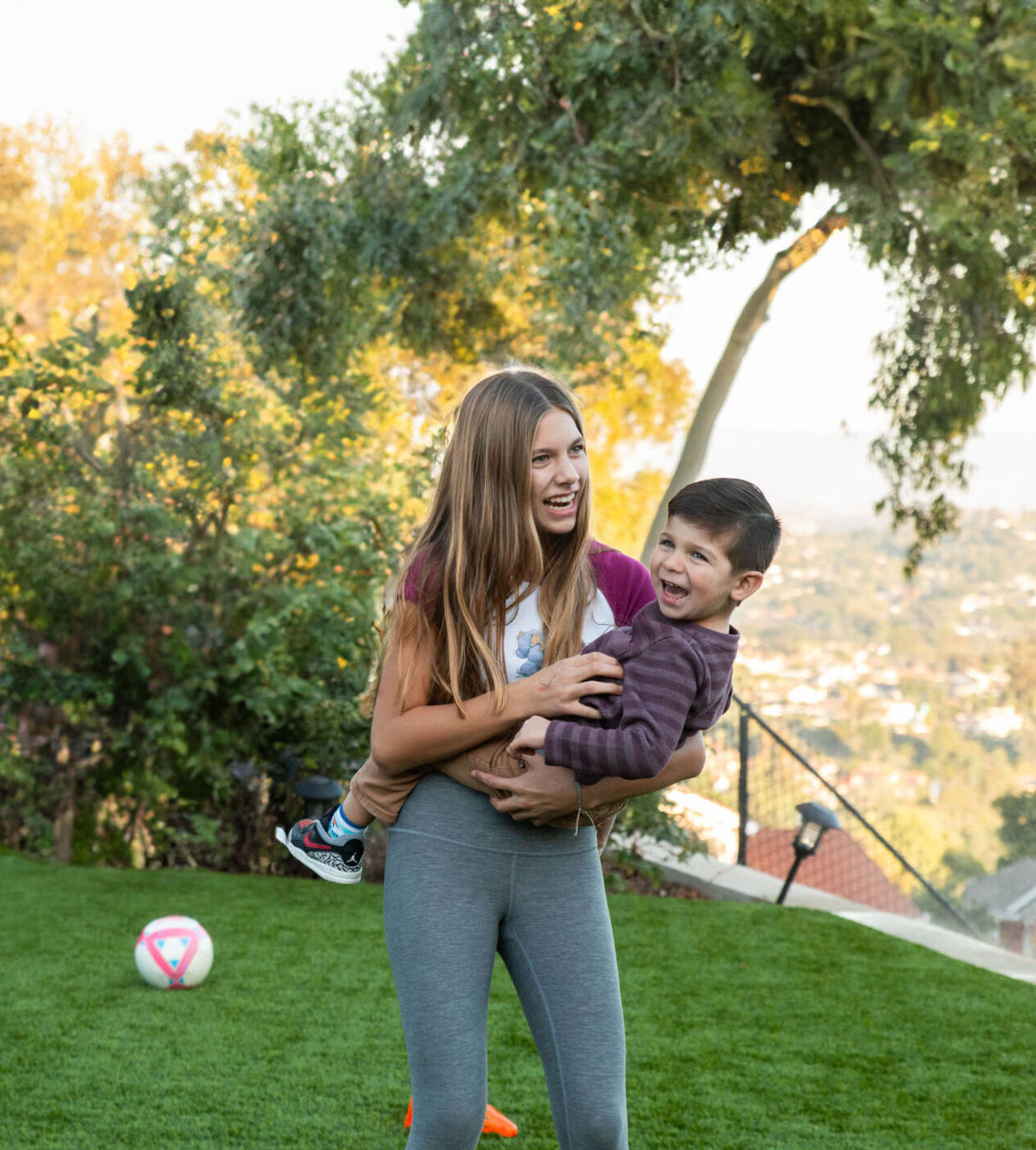 Family Fun on TurFresh-Maintained Artificial Turf – Safe & Clean Outdoor Living Sister playing with younger brother on clean artificial turf maintained by TurFresh.