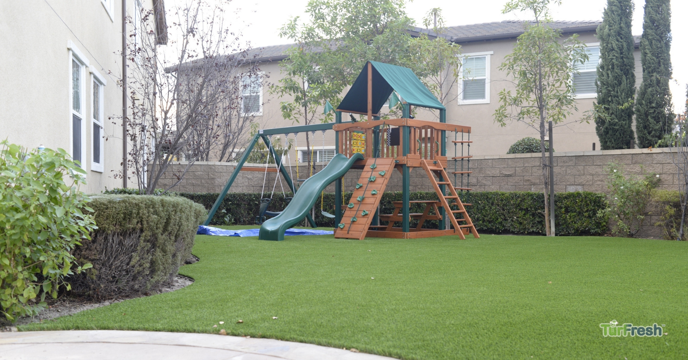 Artificial turf maintenance service brushing leaves from lawn Technician brushing synthetic turf lawn to remove leaves and debris
