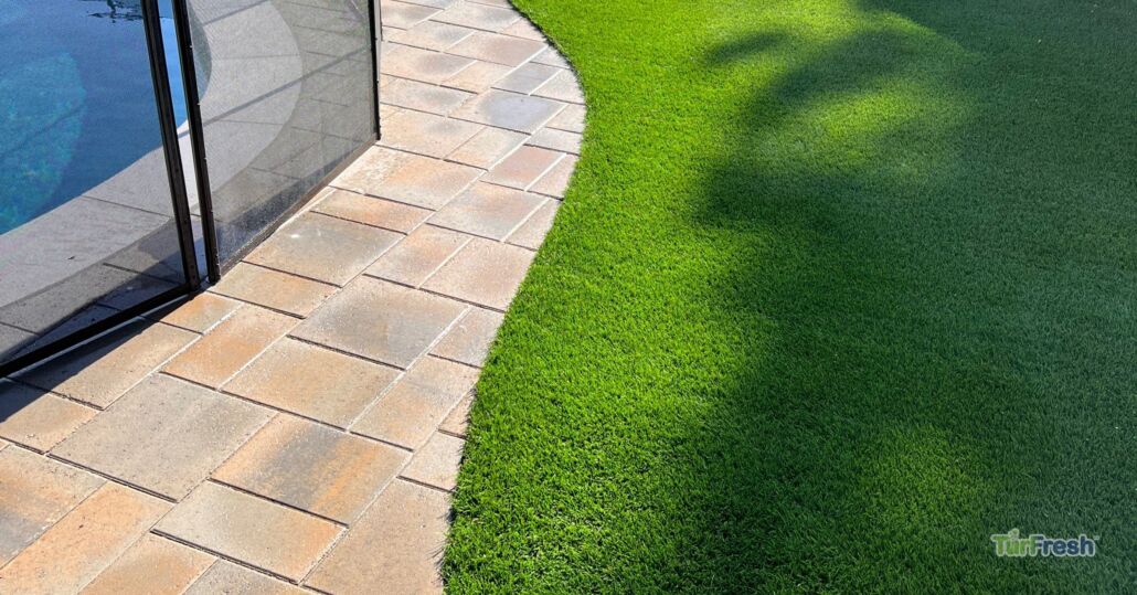 Clean artificial turf lawn beside a pool deck and safety fence, maintained by TurFresh.