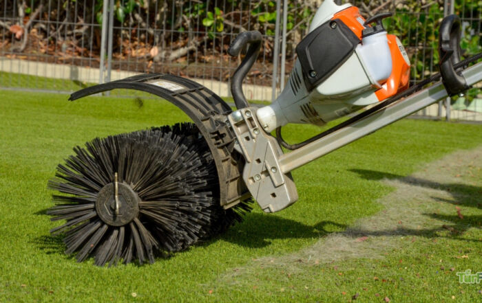 Power broom grooming artificial turf during a TurFresh professional cleaning service to lift matted fibers and remove debris.
