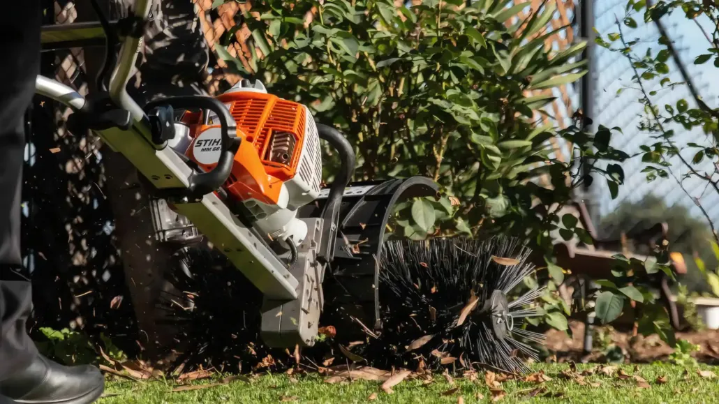 Power broom sweeping leaves off artificial turf during a TurFresh professional turf cleaning service.