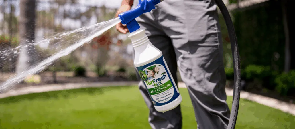 Technician spraying TurFresh artificial turf odor eliminator across a lawn to clean and refresh synthetic grass.